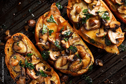 Grilled sandwiches from with various types of mushrooms seasoned with parsley on a grill plate, close up view