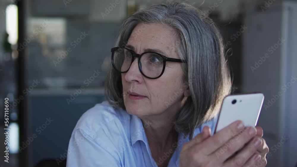 Mature woman online shop manager chatting with annoyed clients on smartphone Mature woman online shop manager chatting with annoyed clients on smartphone