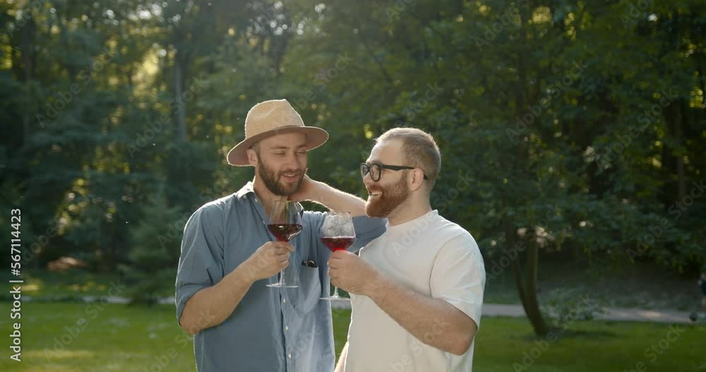 Two happy men drinking wine from glasses in a park Two happy men drinking wine from glasses in a park
