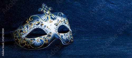 Festive Venetian carnival mask with gold glitter decorations and diamond beads on dark blue background.