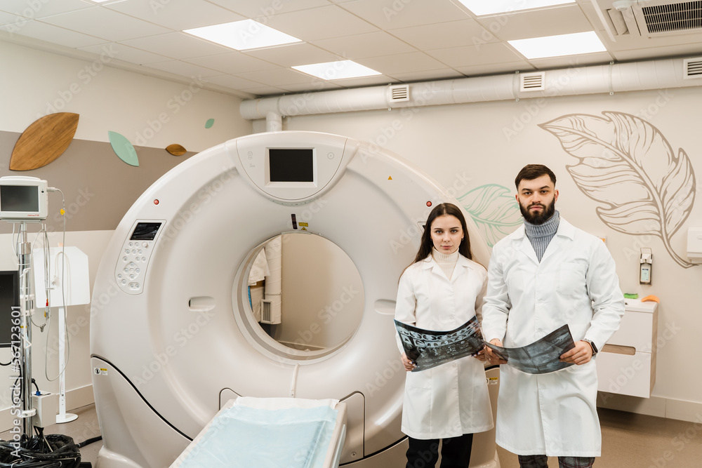 Colleagues radiologists are holding x-rays in their hands after CT computed tomography procedure and discussing diagnosis of patient. Colleagues radiologists are holding x-rays in their hands after CT computed tomography procedure and discussing diagnosis of patient.