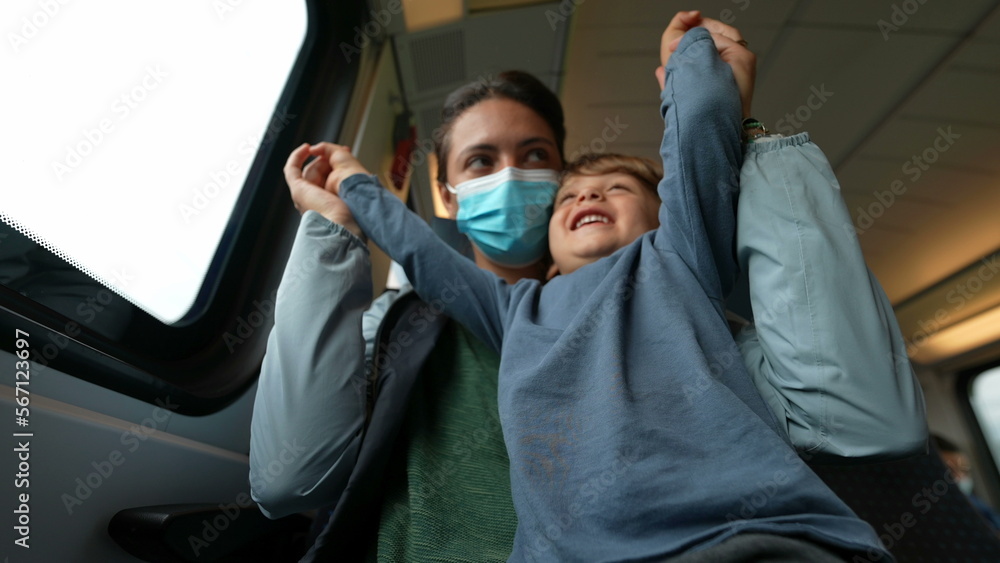 Playful mother and child traveling by train mom wearing surgical face mask prevention against virus