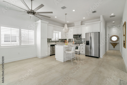 Vacant home with staged white kitchen and large ceiling fan tile flooring