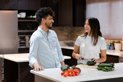 Hispanic couple cooking healthy salad in their kitchen - Young housewife making healthy recipes together with her partner