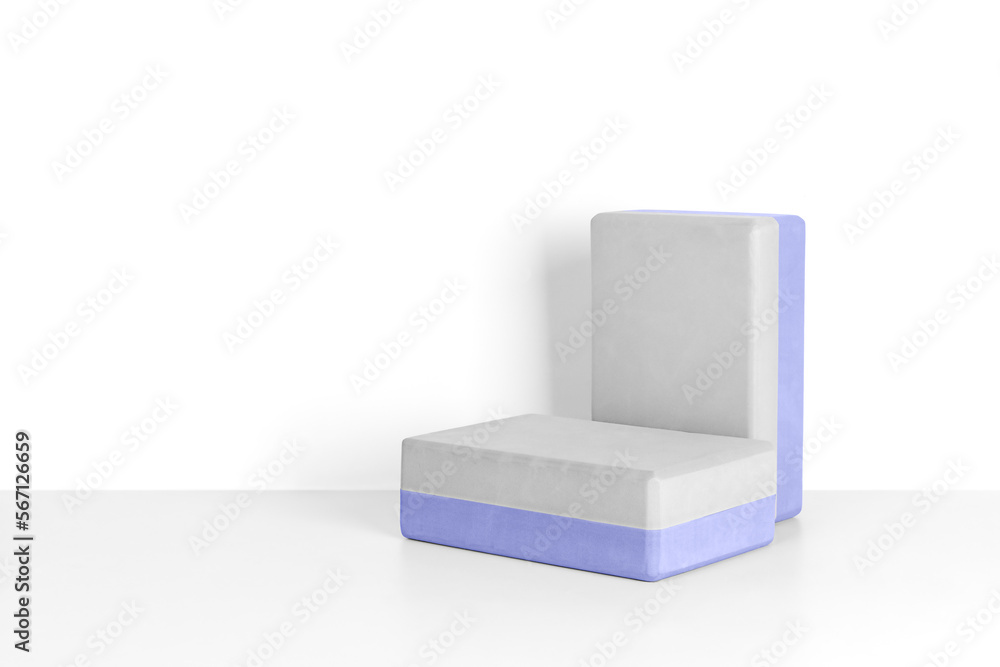 Two yoga blocks on a gray background, front view. A podium of blocks to showcase sports accessories. Fitness and activity. Two yoga blocks on a gray background, front view. A podium of blocks to showcase sports accessories. Fitness and activity.