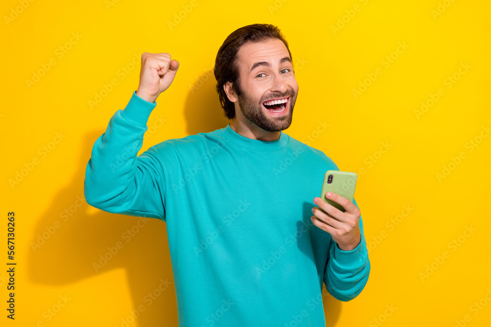 Photo of winning online gambling casino lottery excited guy fist up hold smartphone enjoy get easy internet money isolated on yellow color background Photo of winning online gambling casino lottery excited guy fist up hold smartphone enjoy get easy internet money isolated on yellow color background