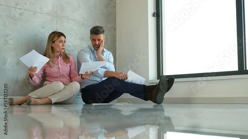 Businesswoman and businessman sitting on floor in office. Overworked female businessperson having problems with paperwork, financial graphic data. Colleague is listening, supporting and comforting her