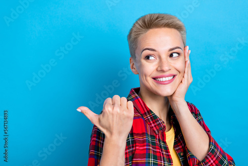 Portrait photo of young funny dreamy cute lady wearing red plaid shirt direct finger mockup touch cheek gift promo isolated on blue color background