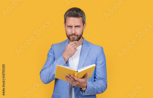 pondering businessman reading planner isolated on yellow background. businessman reading