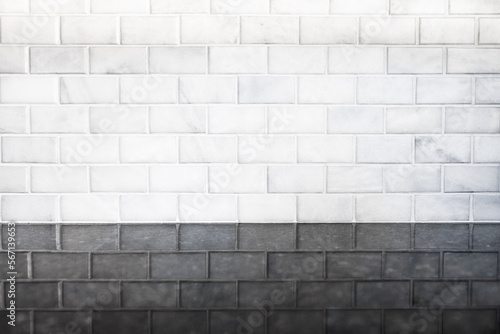 White subway tile background pattern with reflection on black granite stone counter in modern clean sterile kitchen