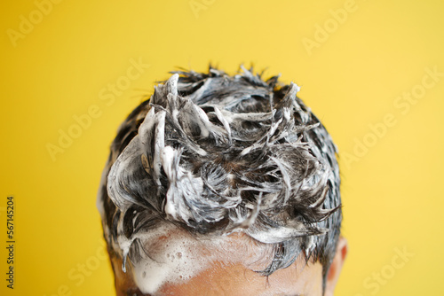 Fototapeta Naklejka Na Ścianę i Meble -  young men washes h his hair with shampoo .