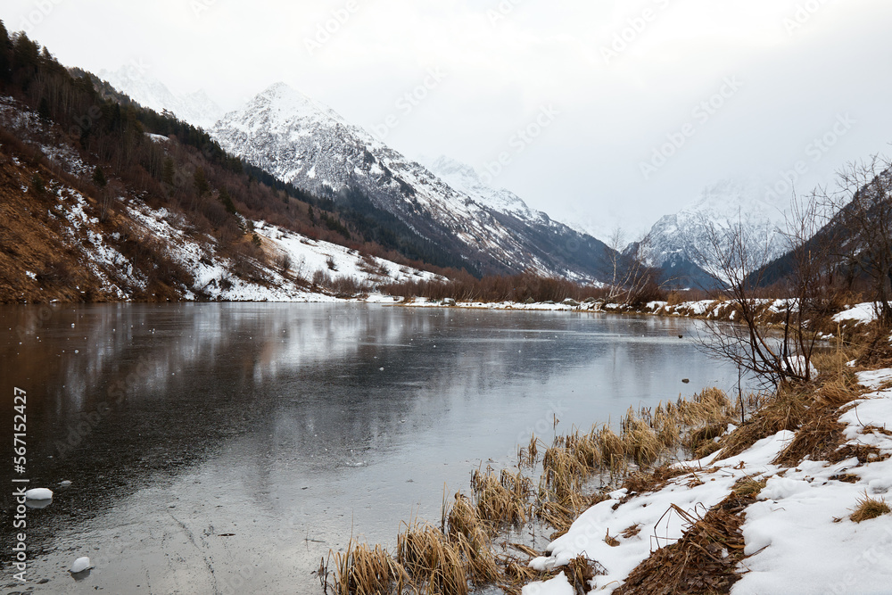 winter mountain lake in snow, in background of mountain, landscape pond with ice on water