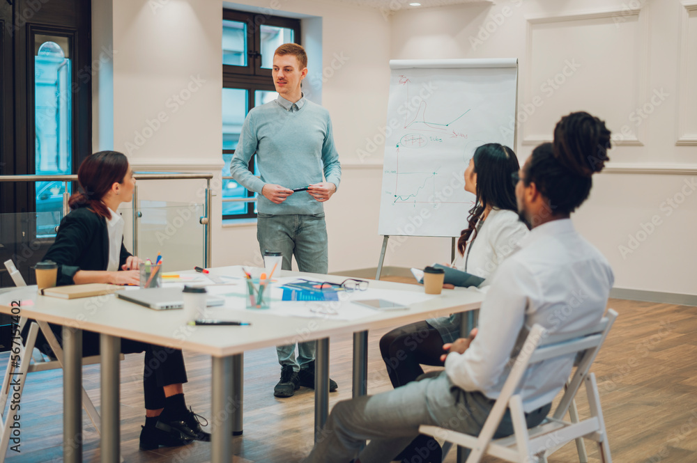 Redhead businessman holding a meeting to his diverse colleagues in an office