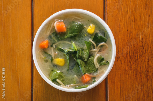 a bowl of soup with vegetables on top of a table