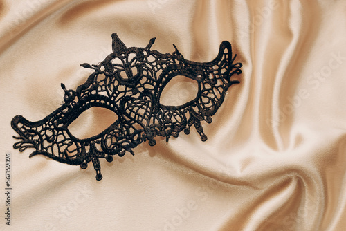 Sexy black lace stylish masquerade mask on golden silk sheet.