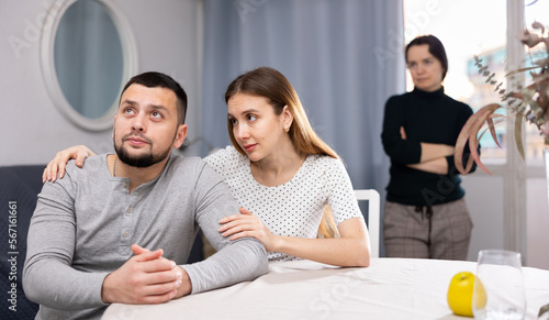 Young woman consoling man during quarreling with his wife at home.