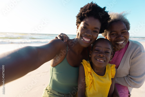 Portrait of african american multi-generation family enjoying at beach against sea and sky in summer © wavebreak3