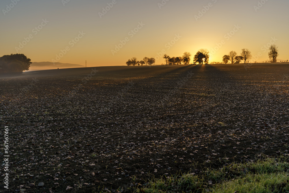 Obraz premium Beautiful sunrise over the mountains in the area of still shaded farmland