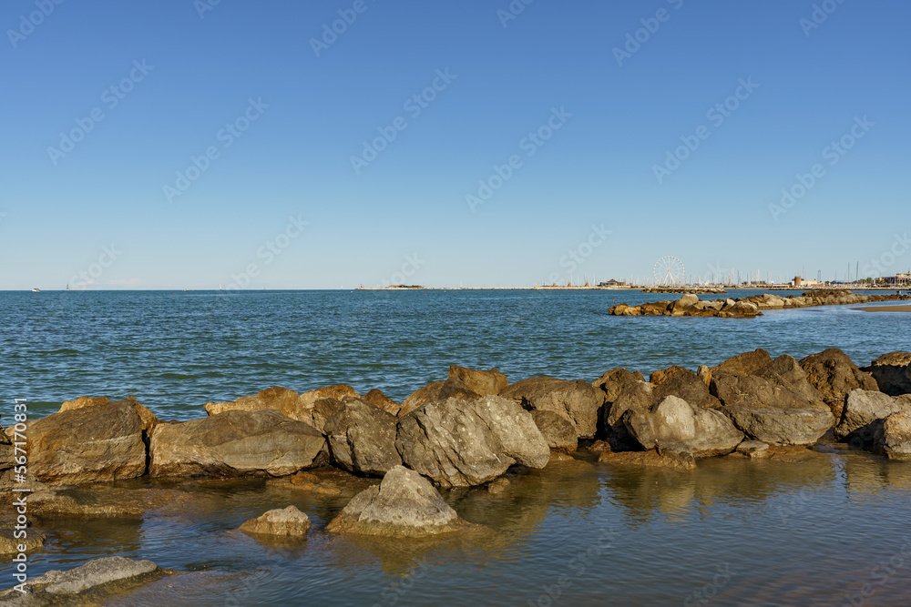 A band of natural rocks forming a natural breakwater protecting the sea beach