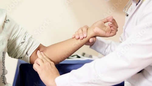 unrecognizable doctor taking woman's brachial pulse in office photo
