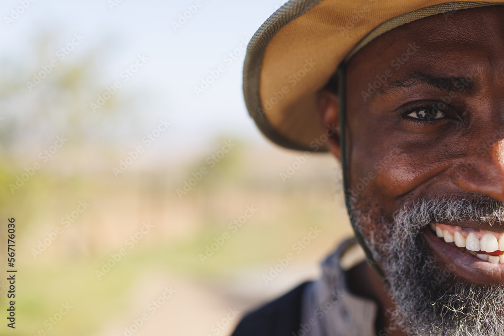 Half face portrait of african american man smiling to camera in nature, copy space Half face portrait of african american man smiling to camera in nature, copy space