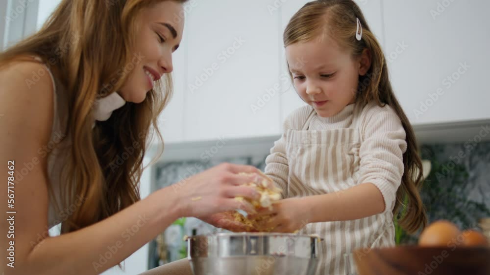 Lovely woman daughter cooking at kitchen. Mom removing pastry from child hands Lovely woman daughter cooking at kitchen. Mom removing pastry from child hands