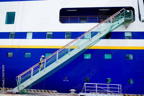 A passenger climbs the gangway of a cruise ship in a traditional vietnamese hat, Ho Chi Minh city, Vietnam. photo