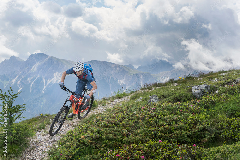 Mountain biker riding on uphill in alpine landscape, Trentino-Alto Adige, Italy Mountain biker riding on uphill in alpine landscape, Trentino-Alto Adige, Italy