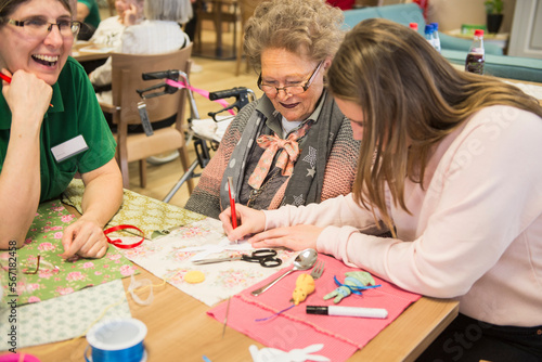 Senior women with girl and nurse doing craft activity at rest home photo