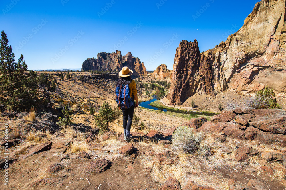 A Girl standing and looking at Beautiful Landscape Scenic of Road Following River Through Valley Surrounded by Tall Rocky Cliff Formations