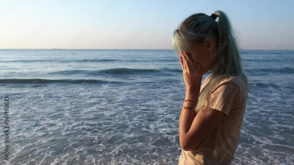 Crying girl by turquoise sea. An upset young girl stay on the beach against blue sea and summer sky. Crying girl by turquoise sea. An upset young girl stay on the beach against blue sea and summer sky.