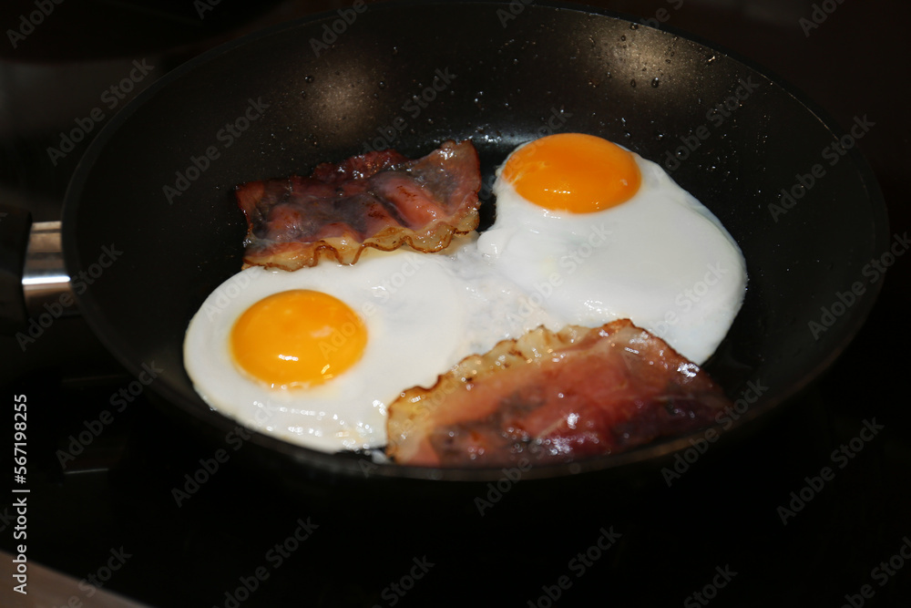 Cooking eggs with bacon in frying pan, closeup. Tasty breakfast Cooking eggs with bacon in frying pan, closeup. Tasty breakfast