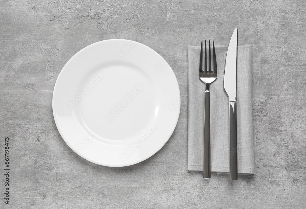 Clean plate and shiny silver cutlery on light grey table, flat lay Clean plate and shiny silver cutlery on light grey table, flat lay
