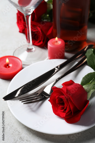 Beautiful place setting with dishware, candles and rose for romantic dinner on light table, closeup
