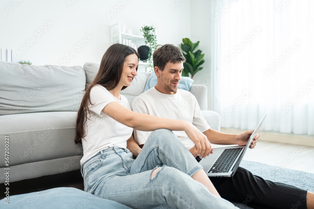 Caucasian young couple using laptop computer in living room at home. Caucasian young couple using laptop computer in living room at home.
