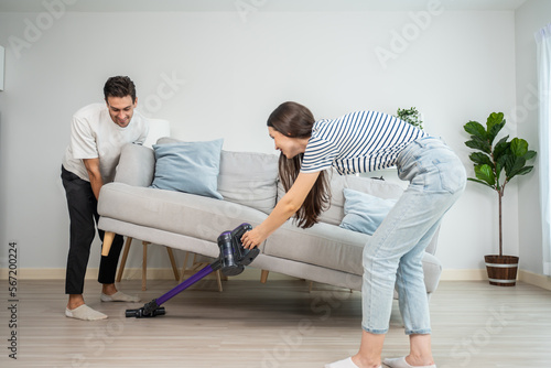 Caucasian young man and woman cleaning living room together at home. 
