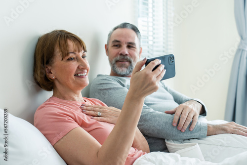 Caucasian senior couple video call with family in bedroom in house. 