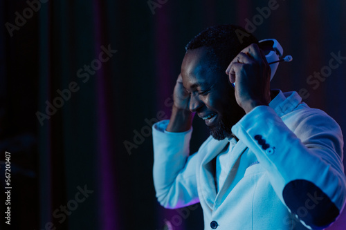 Neon light. portrait of a smiling man in headphones. Listening to music. a man in a white jacket and trousers.