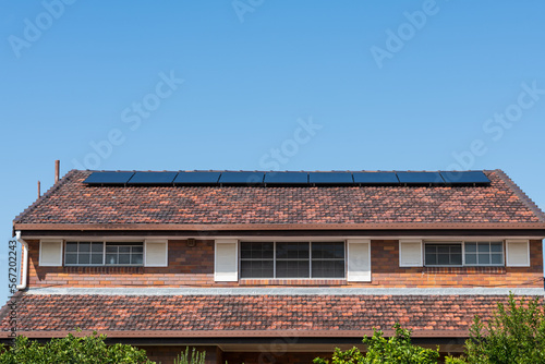 Renewable clean green energy saving efficient photovoltaic solar panels on tiled roof of home, with copy space and blue sky photo