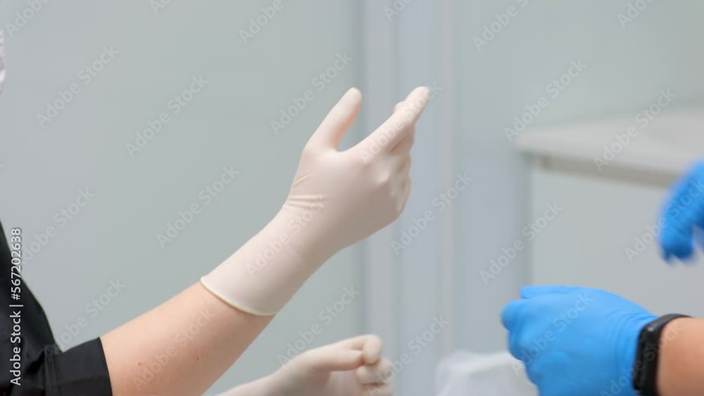 Individual protection products vinyl disposable gloves in spread of virus and protection against infections. Women is dressing hands in gloves nurse putting on washable surgical gloves to doctor Individual protection products vinyl disposable gloves in spread of virus and protection against infections. Women is dressing hands in gloves nurse putting on washable surgical gloves to doctor
