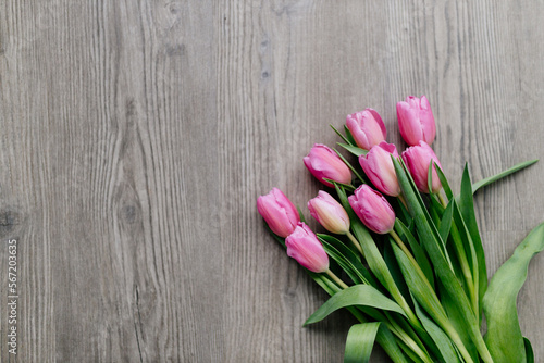Pink tulips lie on a wooden surface. Spring background with flowers. Valentine's day card.