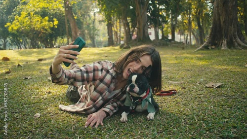 Young woman takes selfie with her Boston Terrier at sunset in park