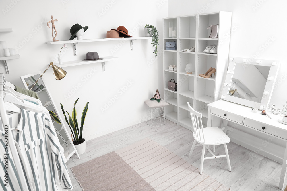 Interior of stylish dressing room with table, shelving unit and clothes Interior of stylish dressing room with table, shelving unit and clothes