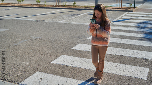 Child clueless in the crosswalk looking the cellphone