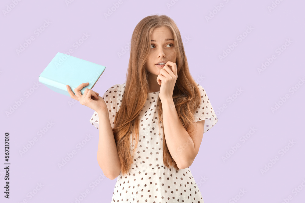 Young woman with book biting nails on lilac background