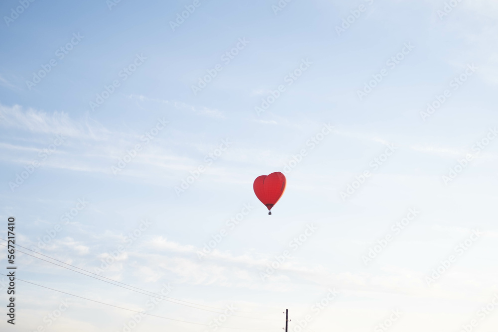 A colorful balloon in the shape of a heart, flying at sunset across the blue sky. Happy Valentine's Day Concept. space for text.