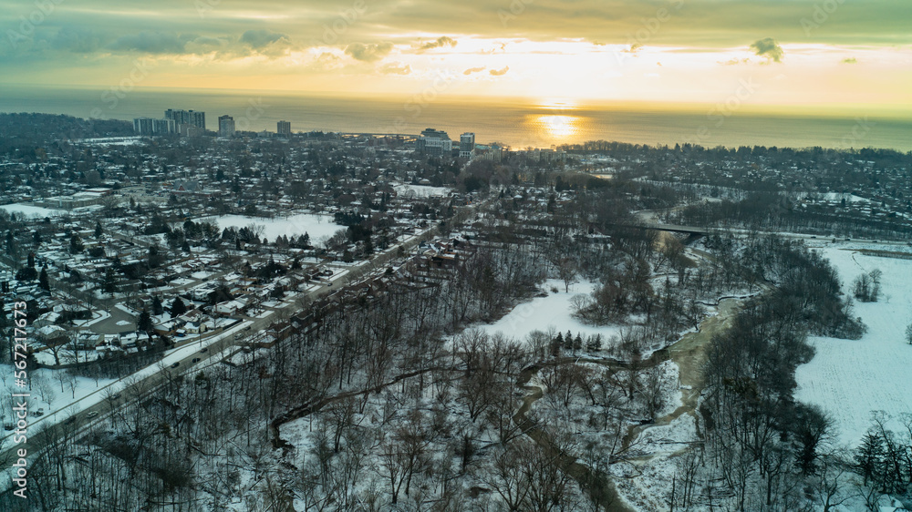 The sun rises over Lake Ontario with a Forest, River and suburbs in the foreground