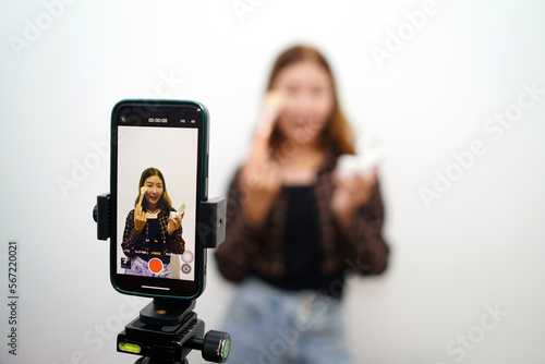 Asian female influencer vlogger getting ready to show how to make up live on IG story reel tiktok at home studio. Gen Z people are filming viral video capture apps.