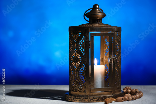 Lantern with burning candle on table against blurred background. Islamic New Year celebration photo