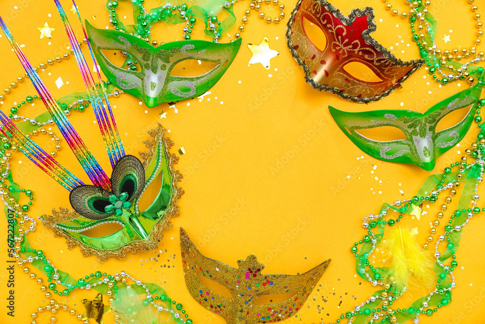 Fototapeta premium Frame made of carnival masks and beads on yellow background